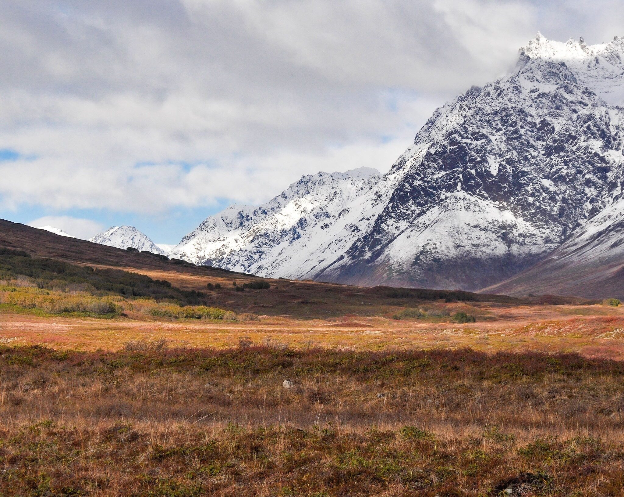Snow-covered mountain landscape under cloud bands.